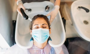 Woman with mask getting hair washed in hair salonhairdresser washing hair in a hairdressing with a mask