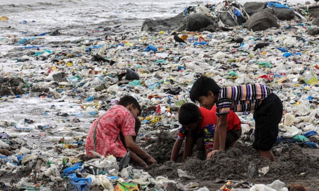 Children plays amid plastic waste near the Arabian Sea coast at Mahim beach in Mumbai