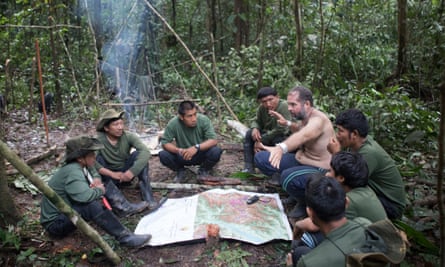 Bruno Pereira gestures over a map while talking to people next to a campfire in the forest