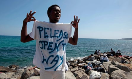 A migrant shouts a slogan as he wears a T-shirt with the message, ‘Open The Way’ as he stands on the seawall at the Saint Ludovic border crossing on the Mediterranean Sea between Italy and France.