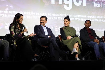 Four people sit holding microphones in front of a cinema screen.