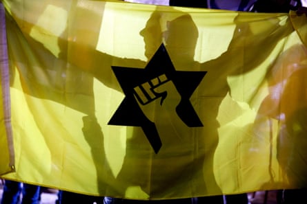 a man is silhouetted done a yellowish emblem that shows a logo of a fist successful nan Star of David