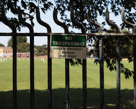Green playing fields behind fence with sign reading: 'No trespassing. Private property beyond this point'