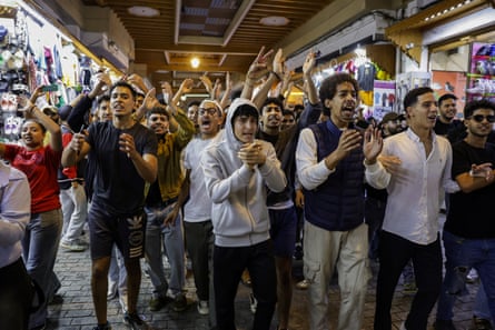 A large group of boys and young men march through a market.