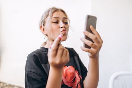 Teenage girl paints her lips in front of her phone