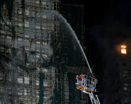 Water is sprayed from a cherry picker towards a burnt out apartment building