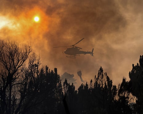 A firefighting helicopter drops water over a wildfire near the village of Larouco, in the province of Ourense, in northwestern Spain.