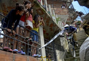 Children watch as a downhill rider competes during the Adrenalina Urban Bike race final