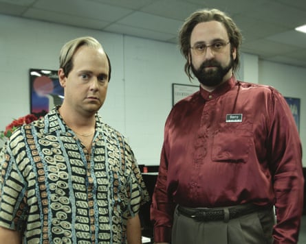 Two men wearing silk shirts and funny hair styles standing in a room