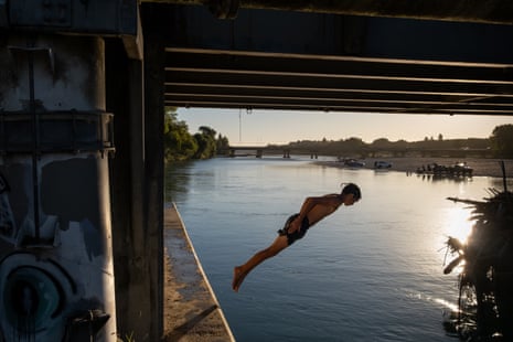 A teenage boy jumps into a river