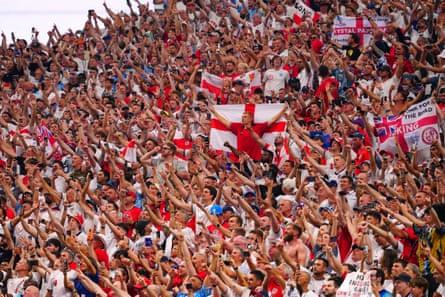 Fans in the crowd wave flags and hold their hands in the air