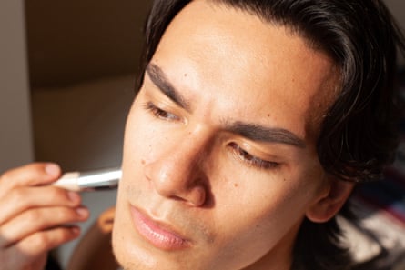 A mixed race man using a makeup concealing stick