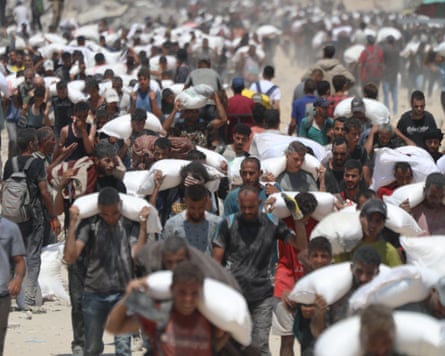 crowds of people carrying sacks of humanitarian aid on their shoulders