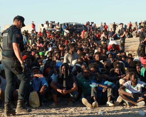 Migrants wait in line to receive food and beverage from the Red Cross, following mass crossings of migrants on foot and by sea from Morocco into Spanish territory, in Ceuta, Spain.