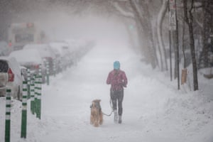 Montreal, Canada: a woman jogs with her dog during a snowfall in Quebec