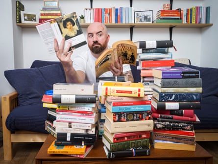 Surrounded by books, Ioan holds one edition of Our Mutual Friend in his left hand and another in his right