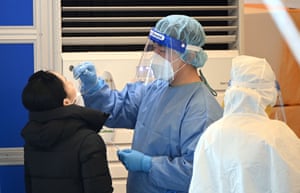 El personal médico toma un hisopo nasal de un visitante como parte de una prueba de coronavirus en un centro de pruebas en Seúl.