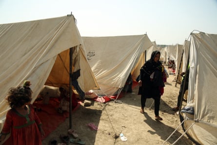 A person affected by floods walks among tents at a temporary camp in Multan district, Punjab province, Pakistan.