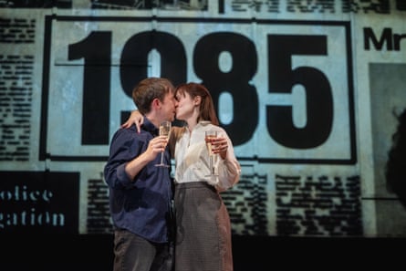 In a scene from Our Friends in the North, a couple kisses holding champagne glasses before a '1985' backdrop