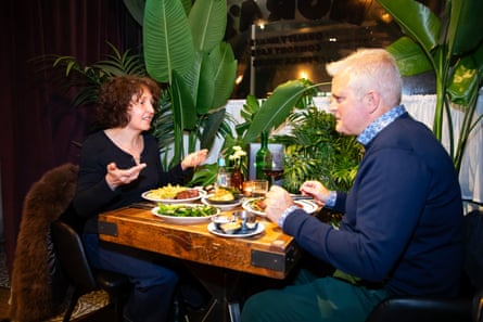 A woman and man facing each other across a restaurant table