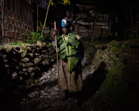 A man stands with a stick in front of a rocky pathway