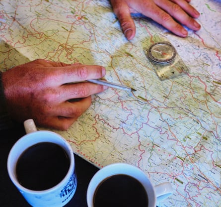 close up of hands on a map with two cups of tea