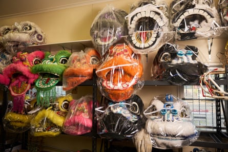 Brightly coloured lion head costumes hang on a wall