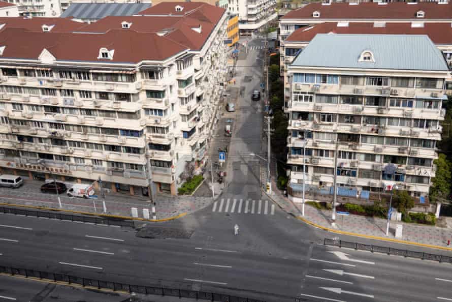 An official in personal protective equipment walks across an empty street during the Covid-19 lockdown in the Yangpu district in Shanghai on 1 April.