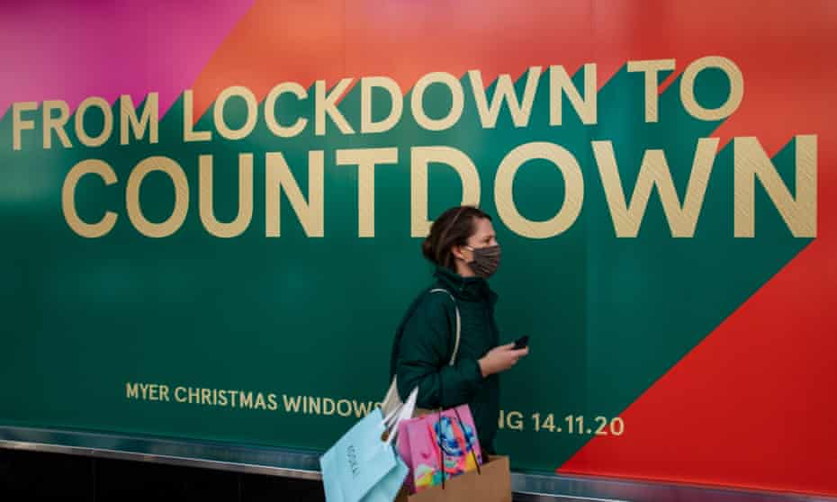 woman wearing mask walks by coloured sign saying from lockdown to countdown