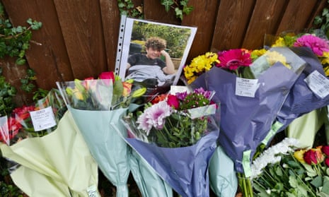 Bunches of flowers and laid against a fence with a photograph of Oliver Stephens on top of them