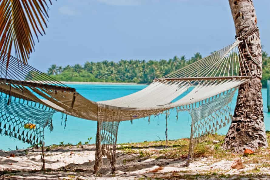 A tattered hammock hangs between palm trees on Direction Island in Cocos Keeling