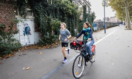 A female jogger and a cyclist passing a mural