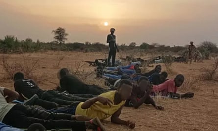 men and boys lie on the ground in open country