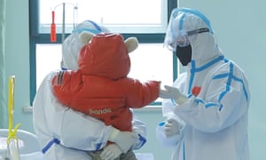 a small child with two people in PPE in a hospital room