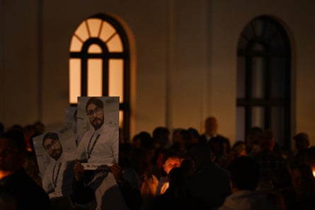 Mourners hold up posters of Faraz Tahir during a candlelight vigil to honour the victims of the Bondi Junction tragedy
