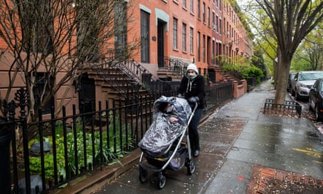 A woman wearing a protective mask carries a baby stroller during the outbreak of the coronavirus disease in the Brooklyn borough of New York City.