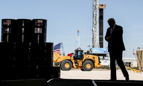 a man in a suit walks near oil barrels
