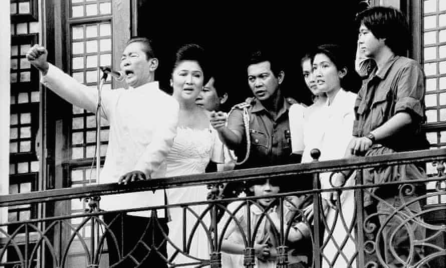 Ferdinand Marcos Jr, far right, watches as his father , far left, makes an address from the balcony of Malacanang Palace in Manila on 25 February 1986