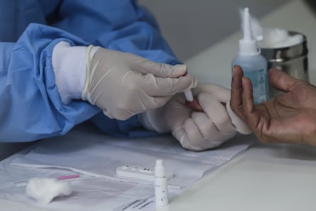 A health worker wearing a protective medical equipment extracts a blood sample from a patient’s finger to make an antibody test for patients suspected of being infected with for the coronavirus (COVID-19) at the Center Health Teixeira de Freitas, in Niteroi, Brazil.