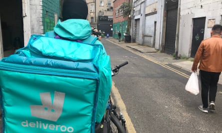 Deliveroo worker Mohammad, from Afghanistan, seen from behind on his bicycle 