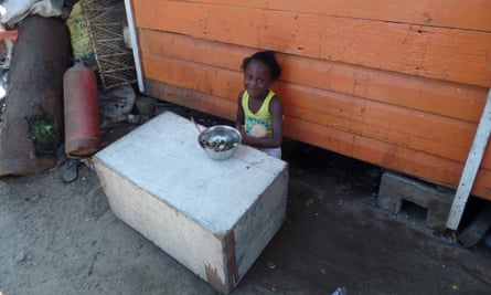 A little girl enjoys a meal of bora and rice outside her Holmes Street Wharf home, Guyana