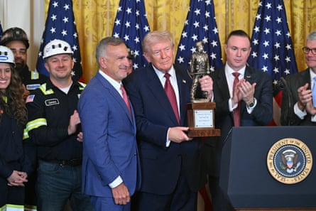 A man holds a trophy and poses next to another man