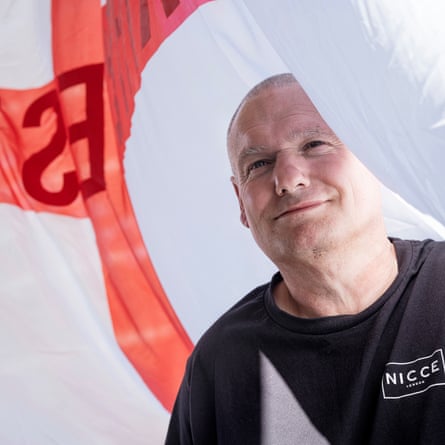 The face of a man smiling as a huge England flag surrounds him