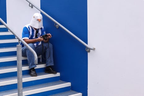 A Brighton fan in a rubber seagull mask sits on a set of steps
