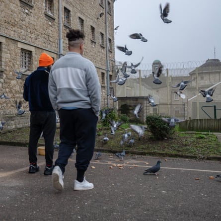 Two men with hands in pockets look at pigeons