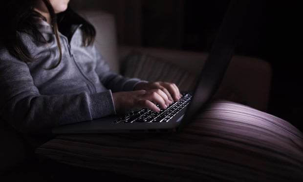 Unrecognisable girl, sitting in a dark, playing with laptop
