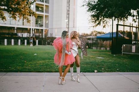 امرأتان أمام العشب خارج الملعب، إحداهما باللون الفضي والأخرى ترتدي فستانًا ورديًا ضخمًا.