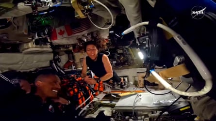 This screengrab from a NASA live broadcast video footage shows NASA astronaut and Artemis II Mission Specialist Christina Koch (R) and NASA astronaut and Artemis II pilot Victor Glover working inside the Orion spacecraft as they pass the halfway point between Earth and the Moon.