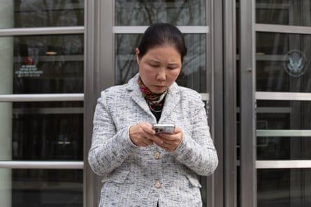 woman standing outside looking down at cellphone