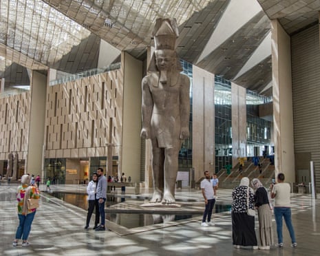 People take photographs of themselves in front of a statue of Pharaoh Rameses II in the main hall of the museum